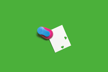 small hole puncher with a paper on a green background