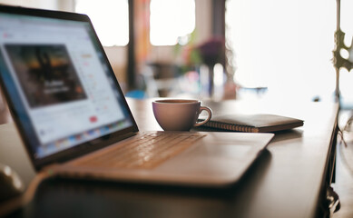 Workplace of business person on desk, focus on coffee cup with book and blure computer laptop