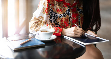 Focus on hand asian businesswoman holding stylus pen writing on digital tablet