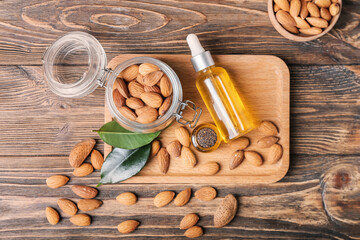 Composition with almond oil and nuts on wooden background
