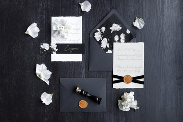 Fototapeta na wymiar Wedding invitation, trendy black background with flower petals. A set of dark wedding printing on a wooden background.