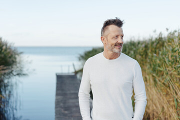 Thoughtful middle-aged man with beard relaxing at the coast