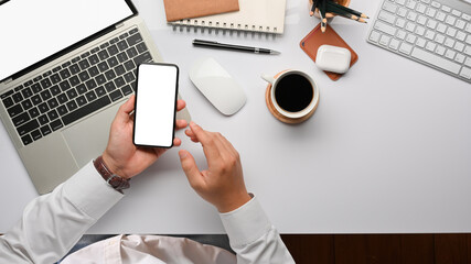Top view of businessman hands using smartphone on office desk with office supplies
