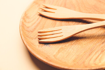 Wooden forks and plate on color background