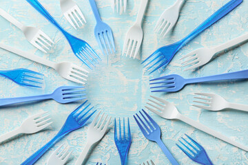 Frame made of plastic forks on color background