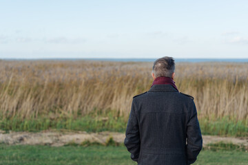 Rear view of a man looking out over wetlands in winter