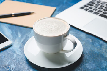 Cup of tasty latte on color background