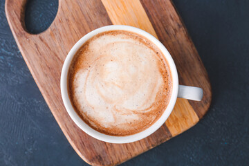Cup of tasty latte on dark background