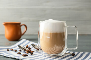 Glass cup of tasty latte on grey wooden background