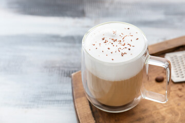 Glass cup of tasty latte on grey wooden background