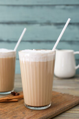 Glasses of tasty latte on color wooden background