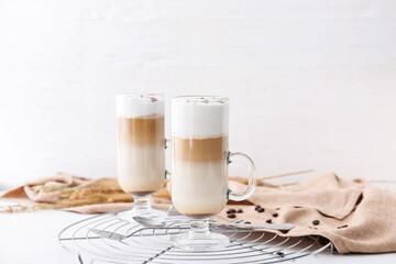Glass cups of tasty latte on light background
