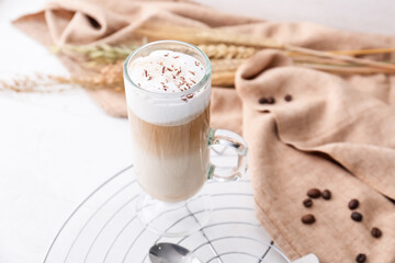 Glass cup of tasty latte on light background
