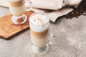 Glass cup of tasty latte on grey background