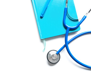 Stethoscope, notebook and pen on white background