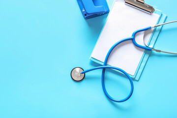 Stethoscope and clipboard on color background