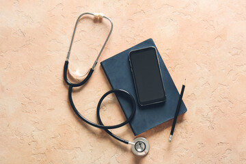 Modern stethoscope, mobile phone, notebook and pencil on color background