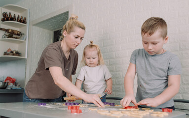 kids help their mom to make delicious cookies at home in the kitchen. joint cooking is a concept of family happiness