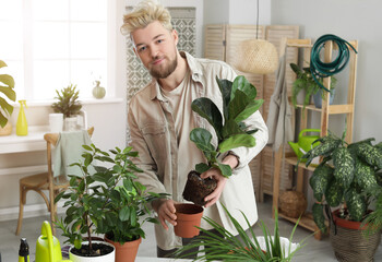 Young man taking care of plants at home