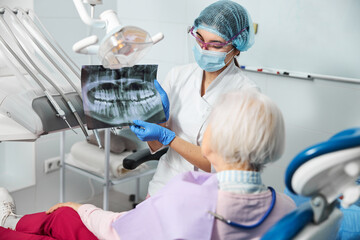 Dentist introducing dental x-ray to a female in medical chair