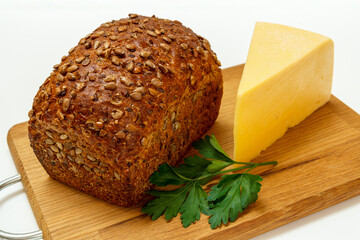 Loaf of bread and cheese on wooden cutting board on white background