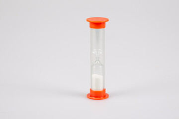 transparent plastic timer hourglass with white sand for measuring time in grey background
