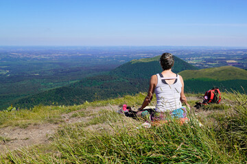 Fototapeta na wymiar sporty woman takes a break in front of the landscape natural panorama of old mountain Puy de Dome volcano in Auvergne france