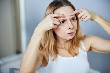 Concerned woman checking wrinkles on her forehead