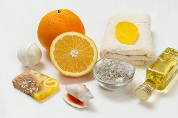 Cut orange with whole one, towel, bottle with aromatherapy oil and sea salt