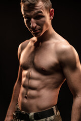 Fototapeta na wymiar Studio shot of muscular topless military man on black background