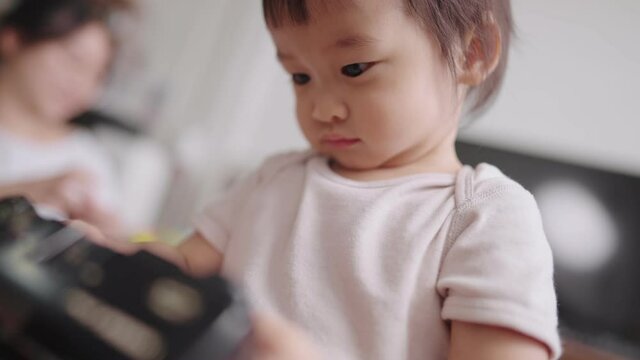 Zoom in portrait of cute female toddler holds camera with looking at camera's screen, acts as photographer screening photos, smile with satisfaction, imitation ability in childhood concept