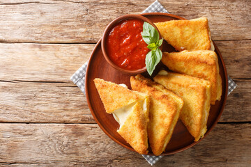 Mozzarella in carrozza is made of sliced bread enclosing the precious creaminess of the mozzarella closeup in the plate on the table. horizontal top view from above