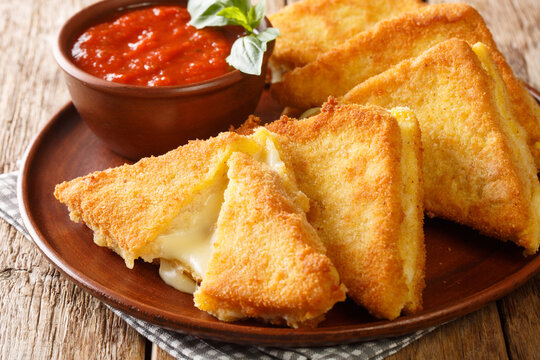 Mozzarella in carrozza is made of sliced bread enclosing the precious creaminess of the mozzarella closeup in the plate on the table. horizontal