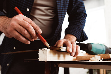 Carpenter makes pencil marks on a wood plank