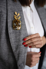 Obraz premium Pineapple brooch from beads and crystals on grey jacket