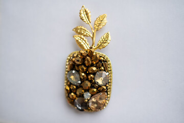 Gold pineapple from beads and crystals on white background
