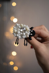 Sheep brooch from beads and crystals on bokeh background