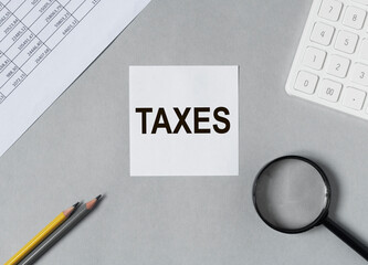 Taxes word on paper, reminder. Taxation concept, accounting and business