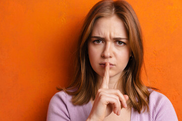 Fototapeta premium Young ginger displeased woman showing silence gesture at camera