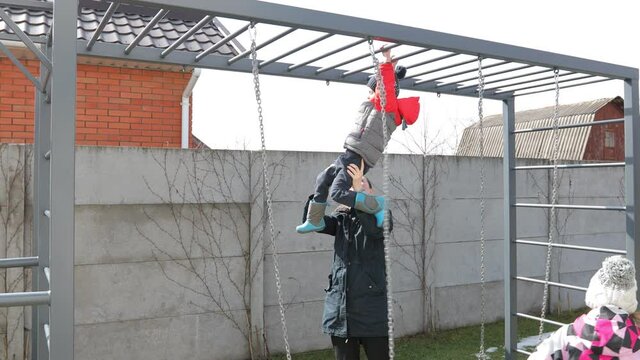Mother helping a child to climb monkey bar