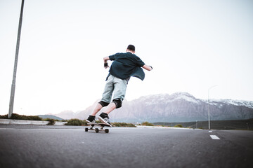 Skateboarder skateboarding on an open road doing freestyle tricks