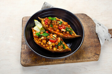 Stuffed sweet potato with spiced chickpea, dressing and herbs.