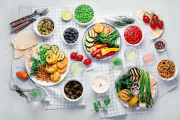 Delicious grilled vegetables with sauces and snacks served on light gray background.