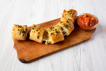 Homemade Chicken Parmesan-Stuffed Garlic Bread on a rustic wooden board on a white wooden...