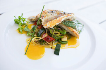 Delicioso pescado cocinado con verduras vista al centro y salsa. Restaurant menu. 