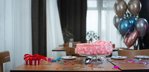 Naklejka na ściany i meble a pink birthday cake stands on the table, a red box with a bow and balloons.