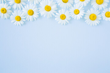 Beautiful fresh white daisies on light blue table background. Pastel color. Empty place for inspirational, emotional, sentimental text, quote or sayings. Closeup. Top down view. - obrazy, fototapety, plakaty