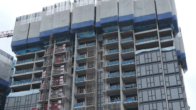 Slow Tilt 4k Footage Of Condominium Construction Site, Windy Day, Tarpaulin Sheets Billowing.