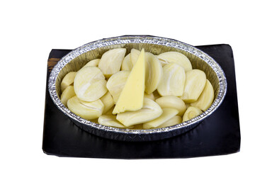 Peeled garlic, sliced ​​in a cup foil on a tile tray.
