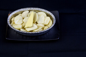 Peeled garlic, sliced ​​in a cup foil on a tile tray.